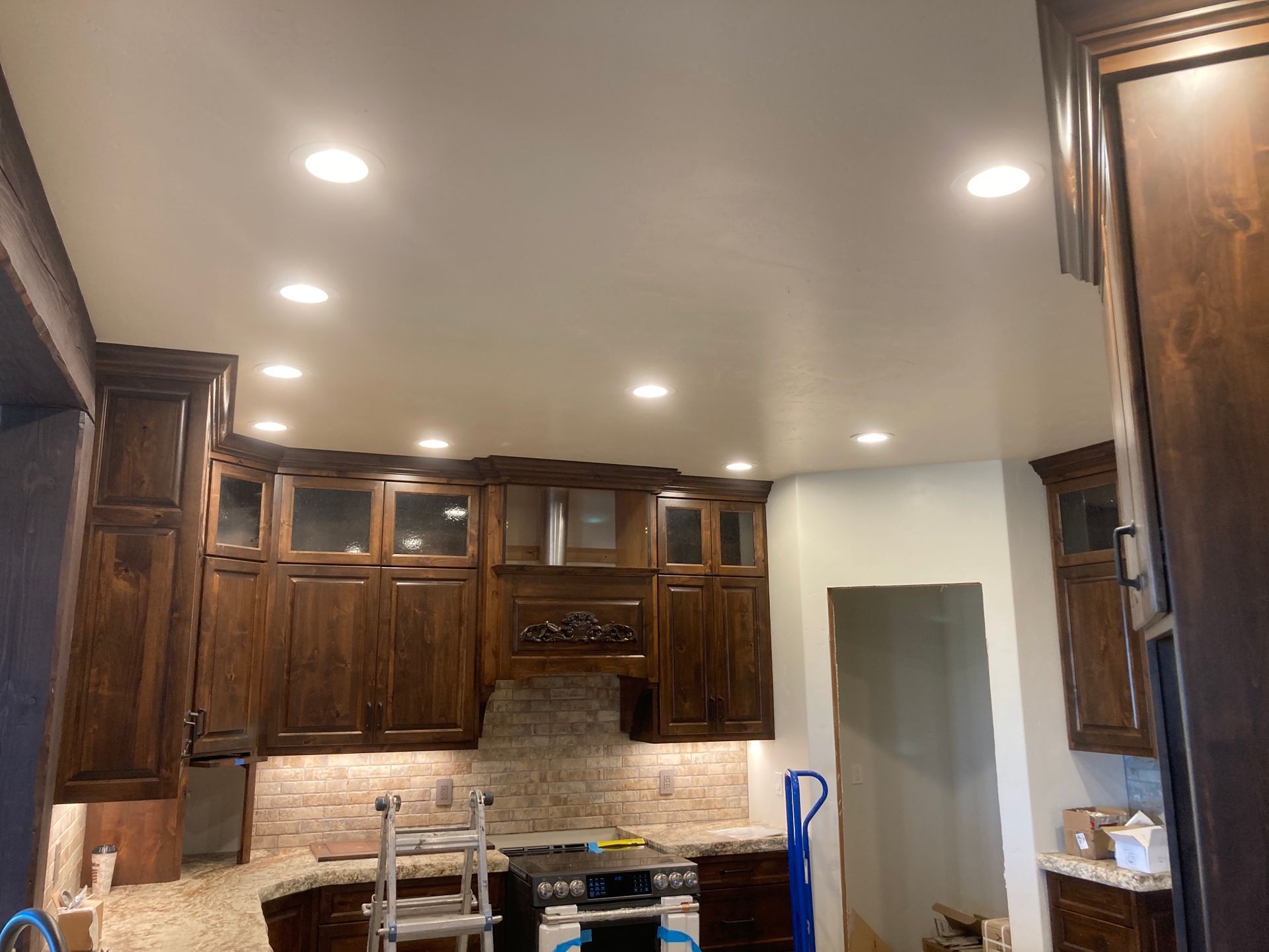 Dark wood kitchen cabinets with recessed lighting; a step stool is in front of the stove.