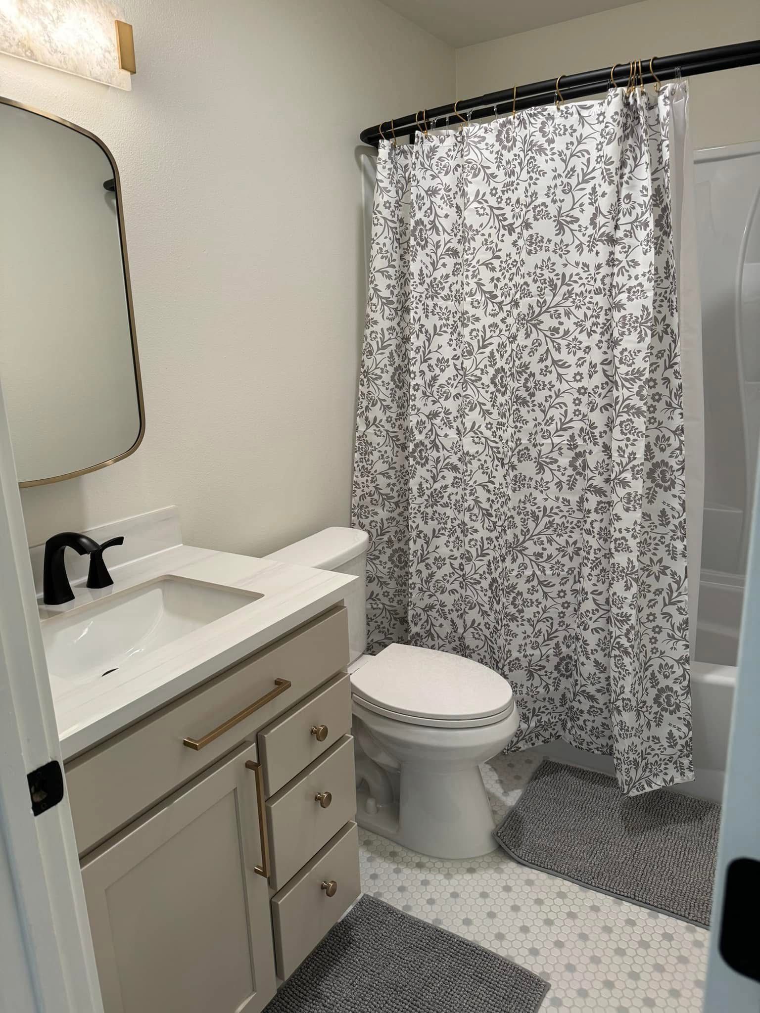 Bathroom with a white vanity, black faucet, patterned shower curtain, and patterned floor.