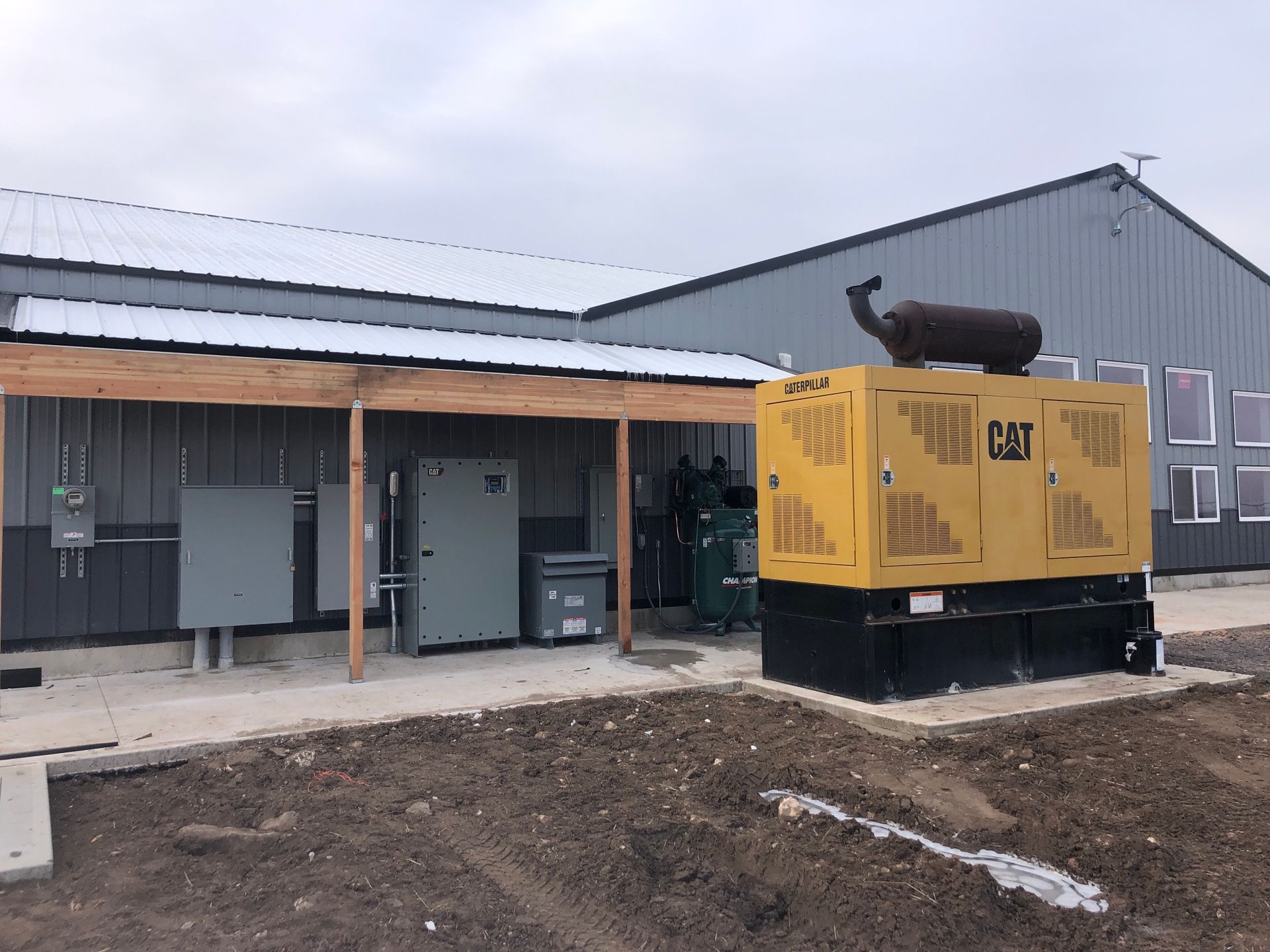 Yellow CAT generator next to a gray building.