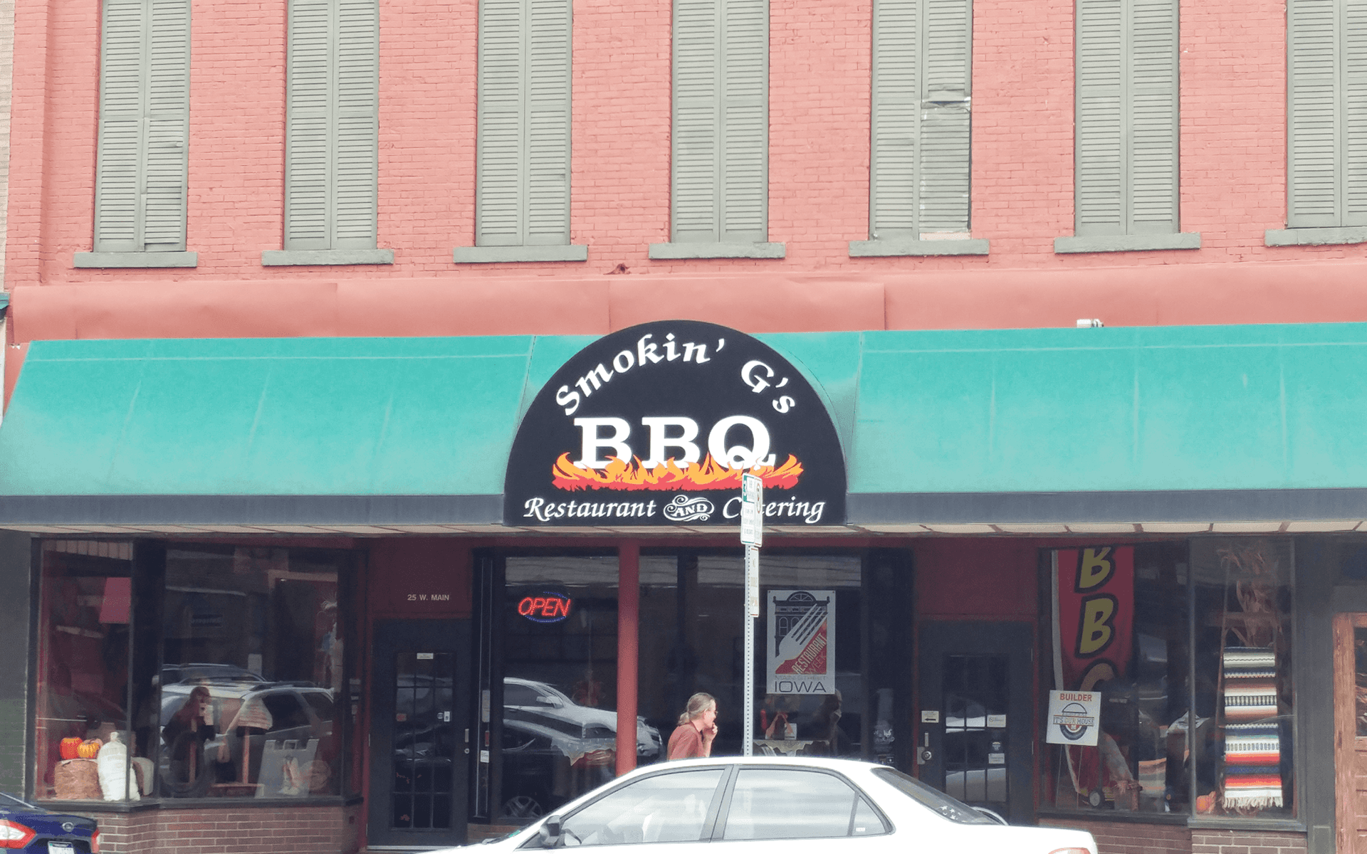 A car is parked in front of a bbq restaurant