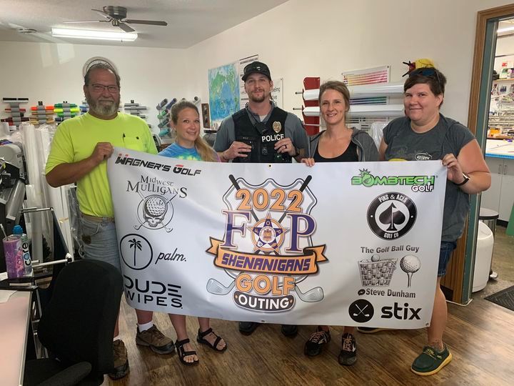 A group of people are holding a banner for a golf outing.