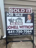 A sold it for sale sign is sitting on the sidewalk in front of a house.