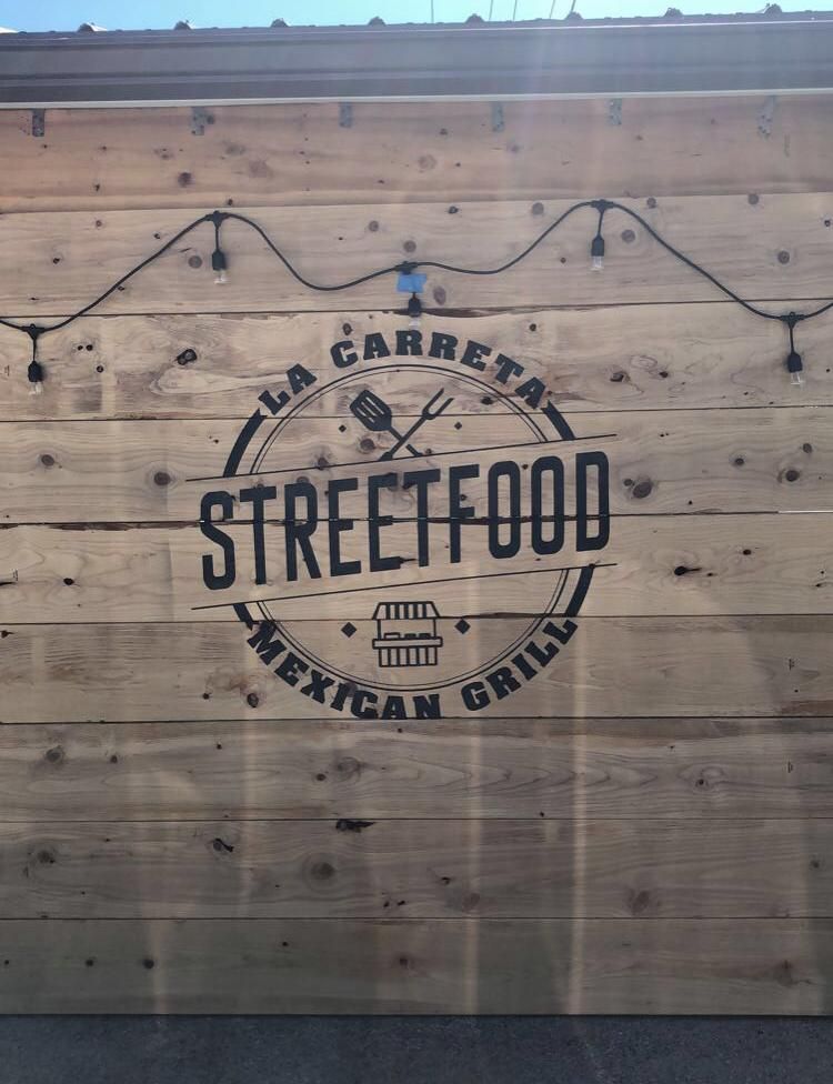 A sign on a wooden wall that says Streetfood Mexican Grill
