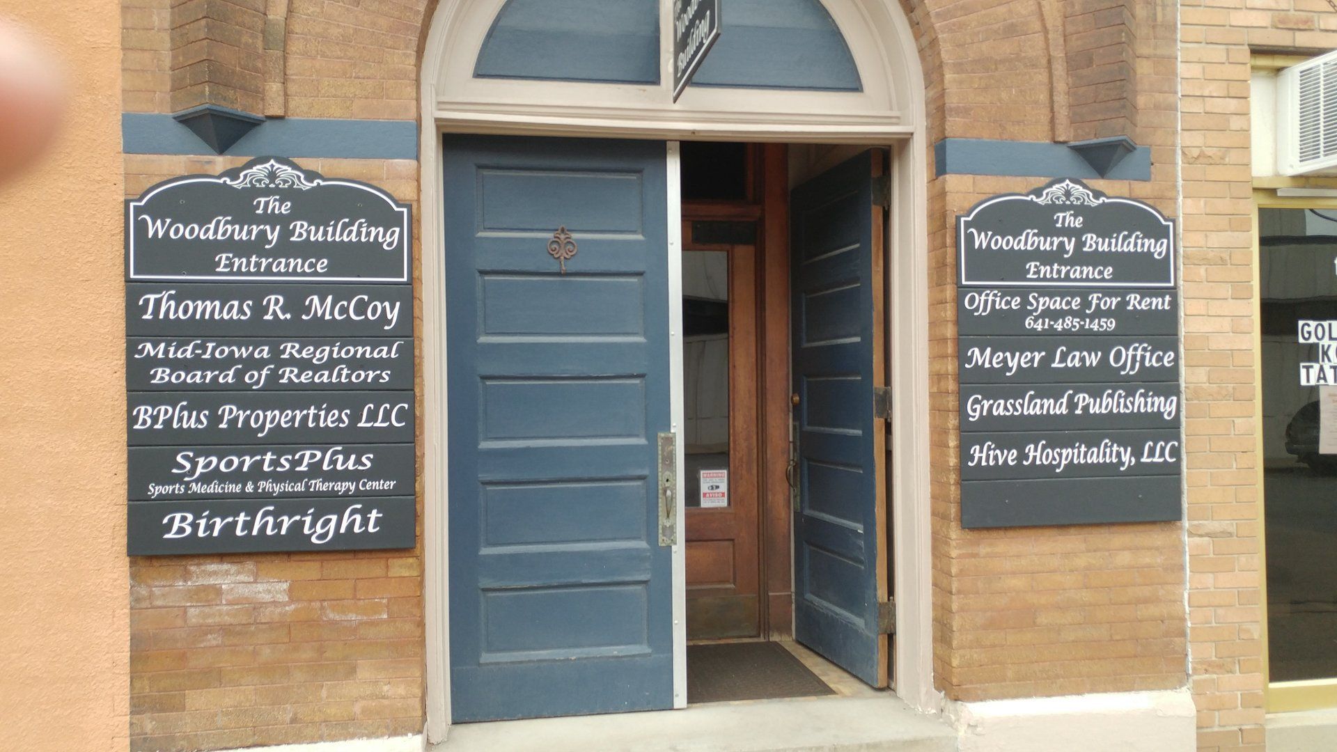 A brick building with blue doors and signs on the side