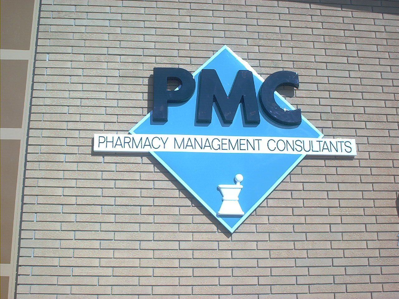 A sign for pmc pharmacy management consultants on a brick building