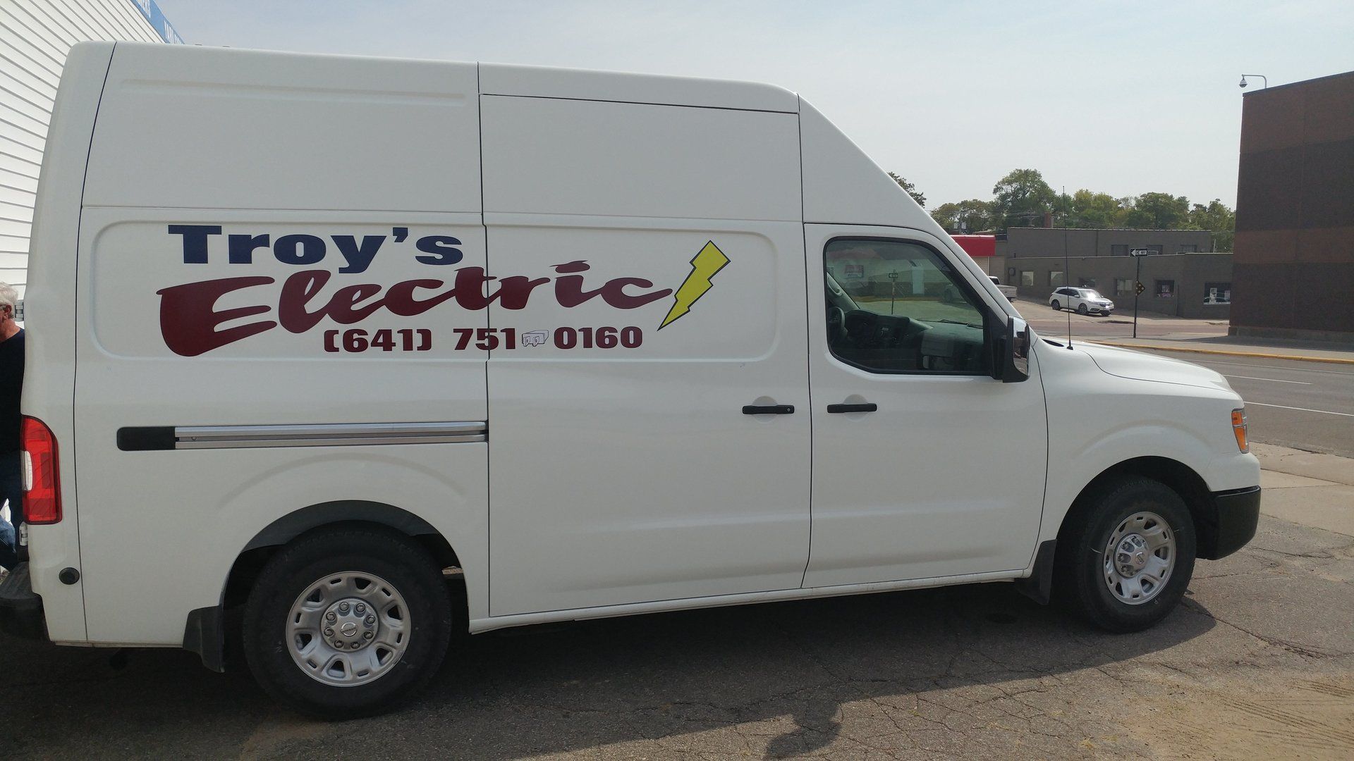 A troy 's electric van is parked on the side of the road