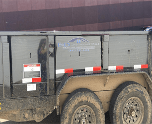 A dumpster trailer with a warning sign on the side