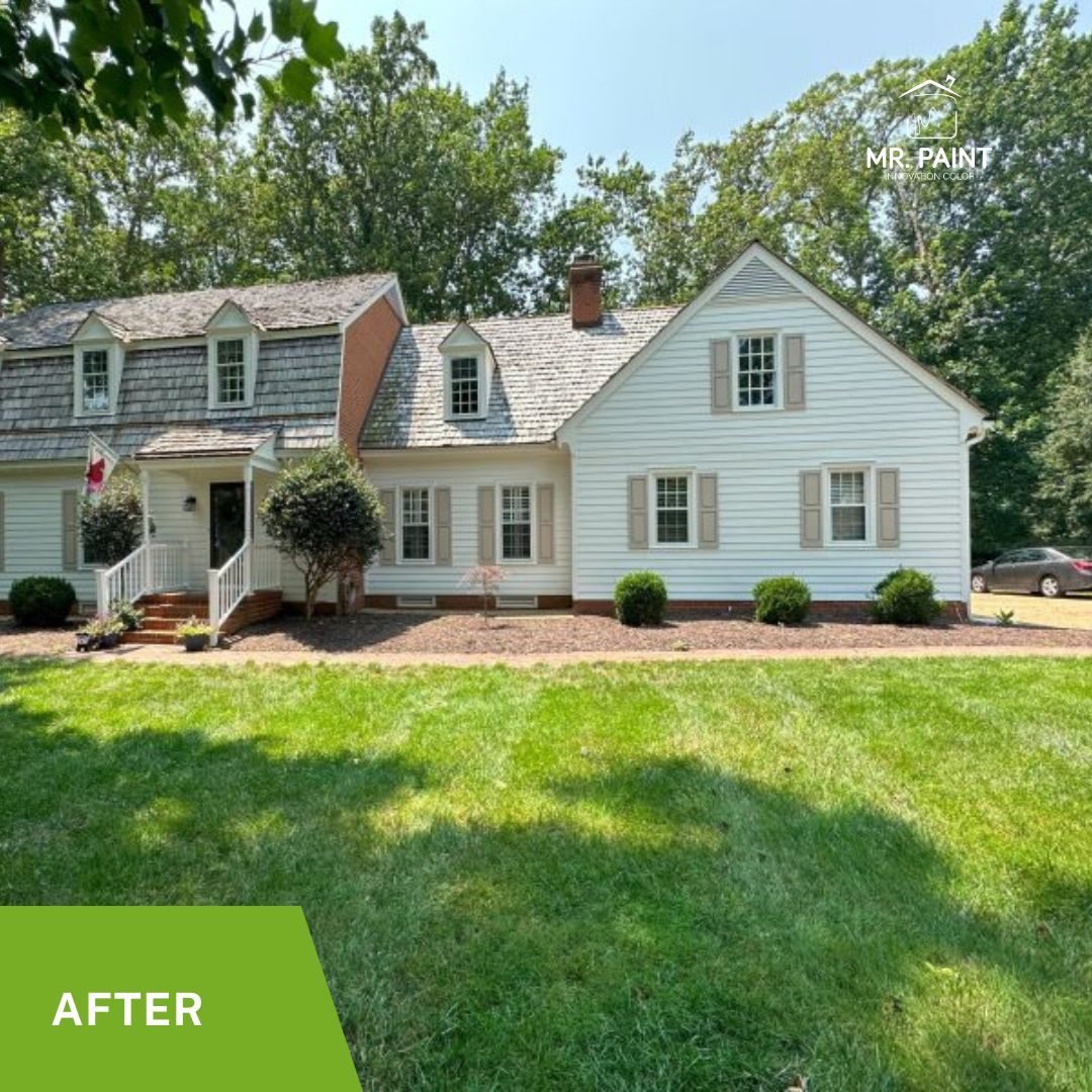White house with brown roof and shutters, green lawn, trees in background, bright sunny day.