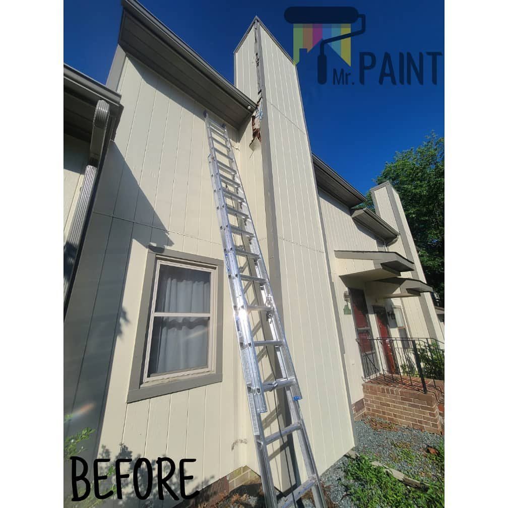 House exterior with ladder, before painting, against a blue sky.