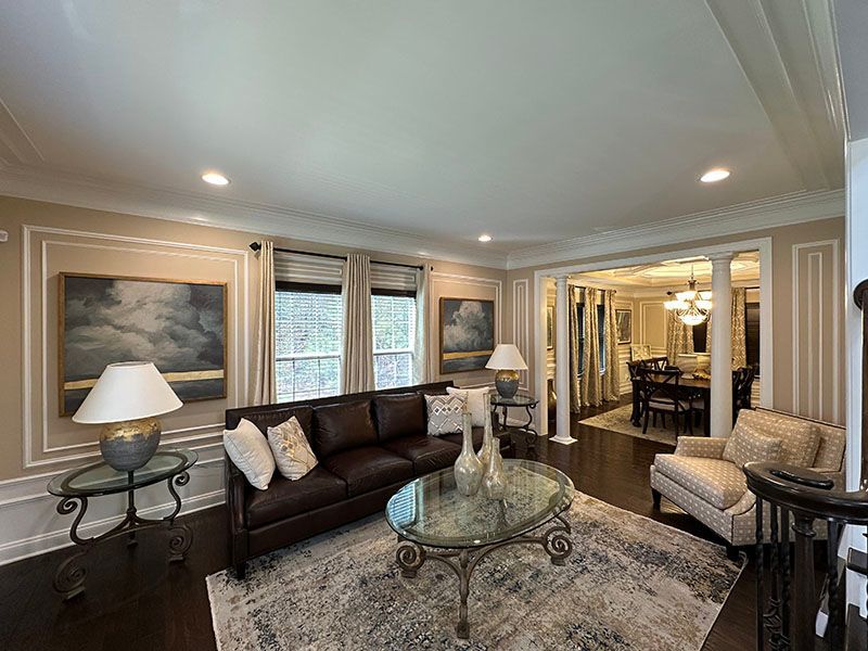 Living room with dark brown sofa, round glass coffee table, and area rug. Artwork on walls.