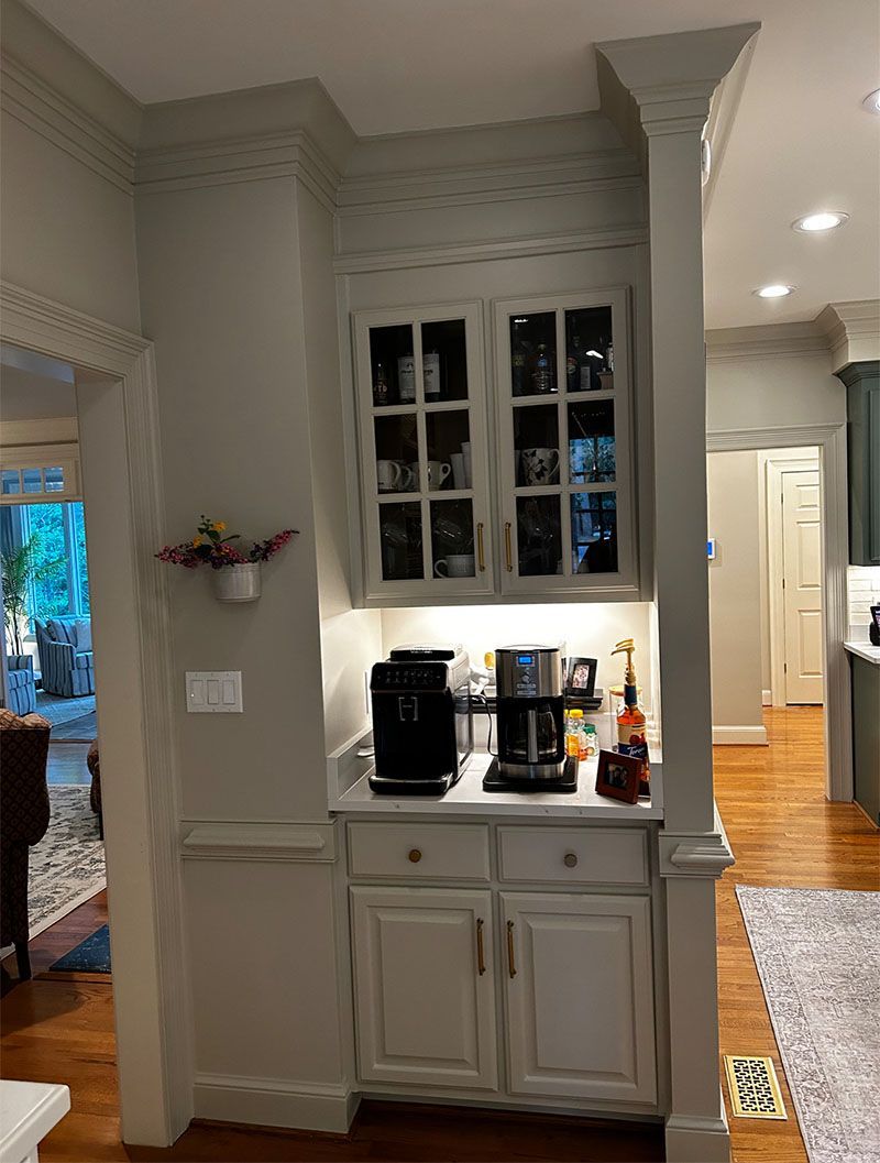 Coffee station with built-in cabinet, two coffee makers, and a wall-mounted flower pot in a kitchen.