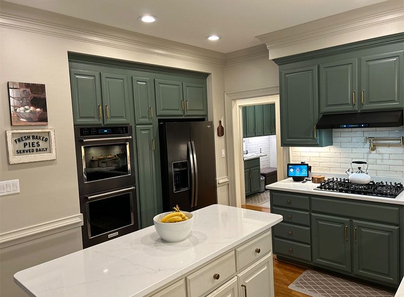 Green and white kitchen with island, cabinets, oven, and refrigerator.