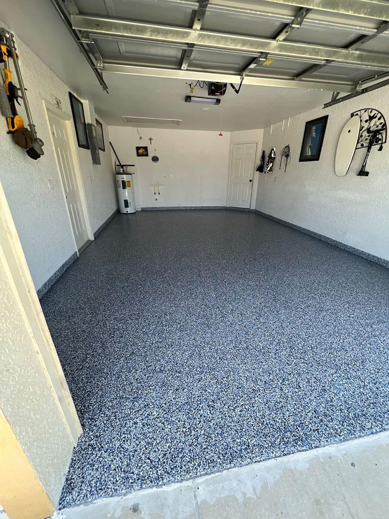 Garage interior with a speckled epoxy floor, white walls, and various items hanging on the walls.