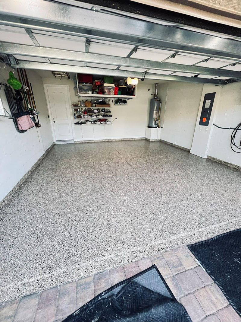 Garage interior with speckled gray floor and overhead storage.