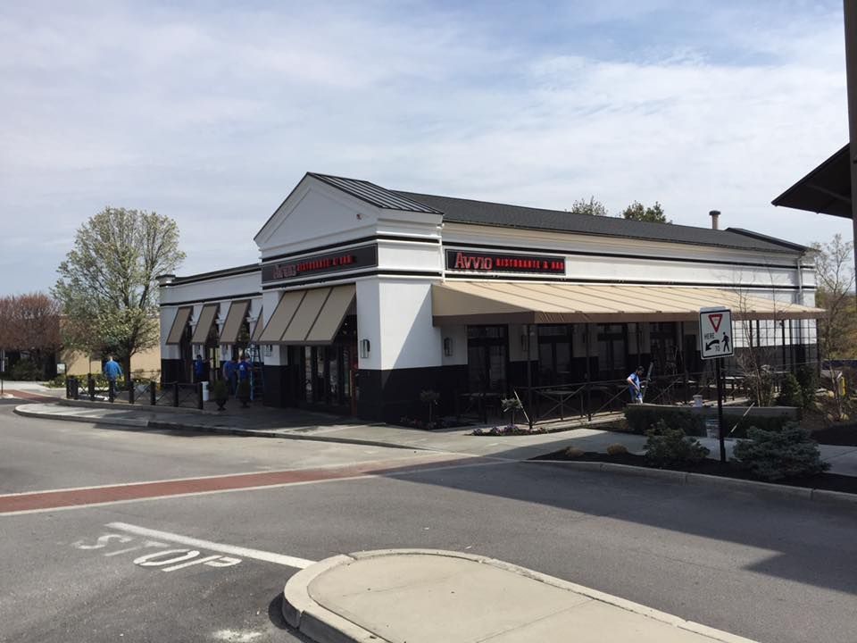 House under construction with wood framing, covered in a moisture barrier, set on a hillside, with a pickup truck in the foreground.