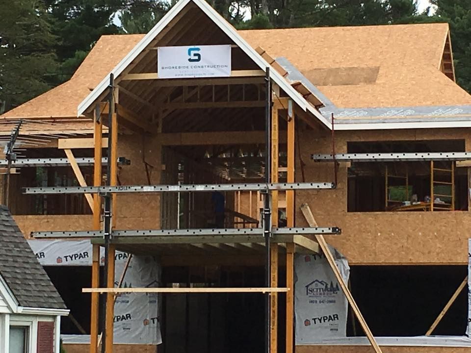 Interior of a restaurant with a dark wood entrance and a large black cabinet. A floral arrangement and lighting fixtures are visible.