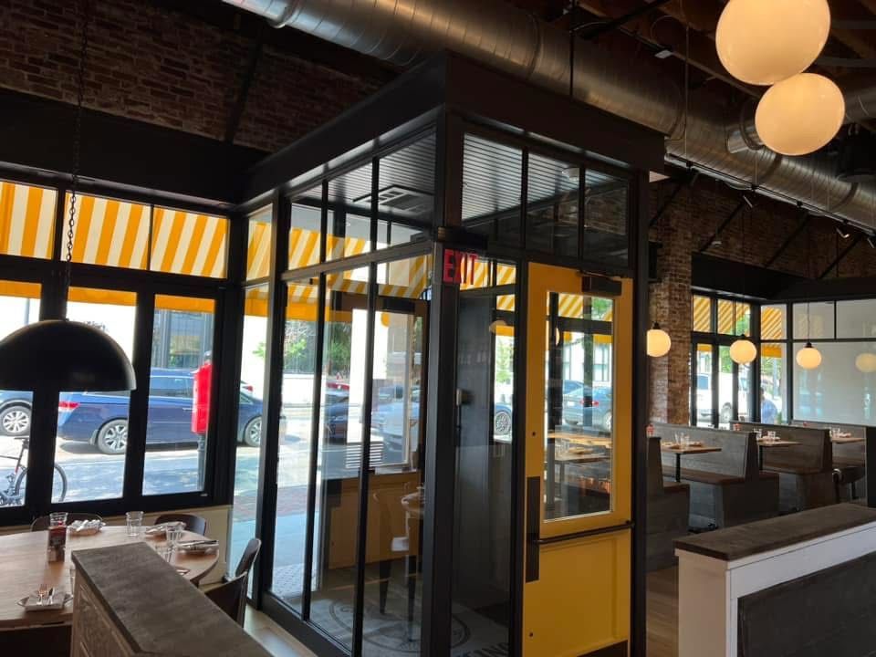 Interior restaurant with a glass-walled structure, awning-covered windows, and yellow accents