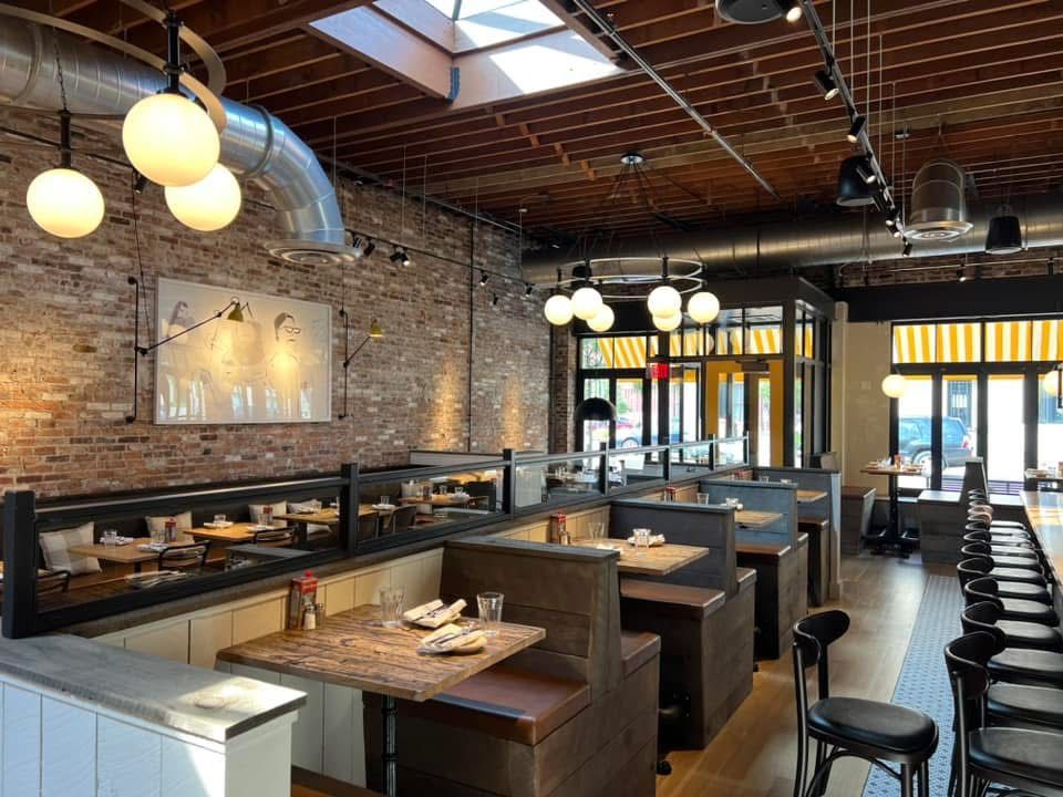 Restaurant interior with exposed brick, booths, bar seating, and globe pendant lights