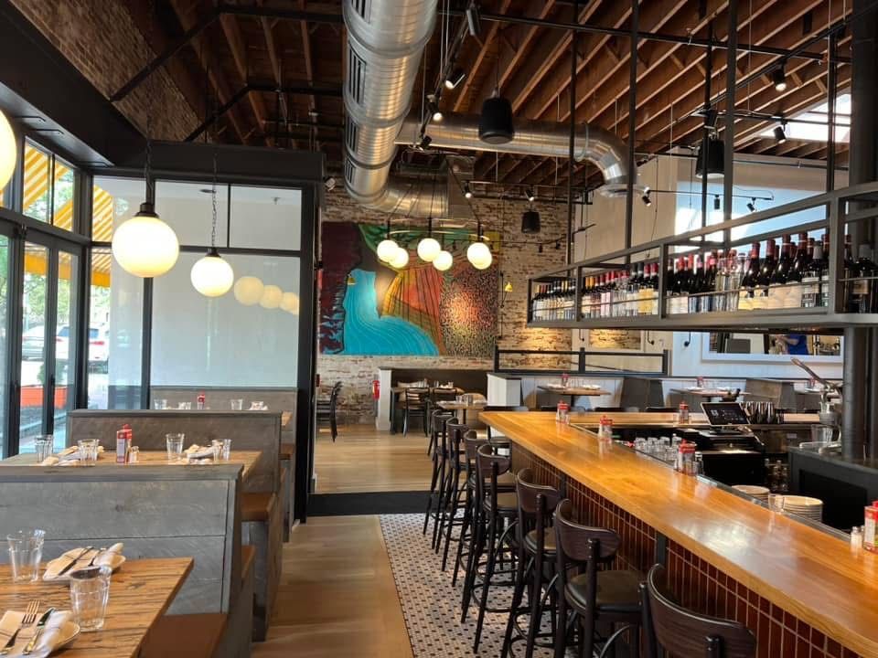Restaurant interior with bar, booths, and a colorful mural