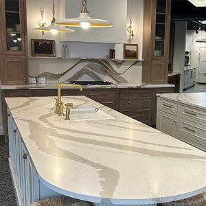 Modern kitchen with curved countertop, gold faucet, and light brown cabinetry.