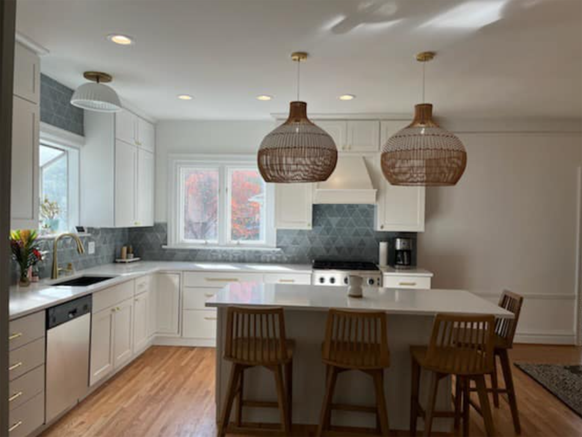 A kitchen with white cabinets, wooden floors, and a large island.