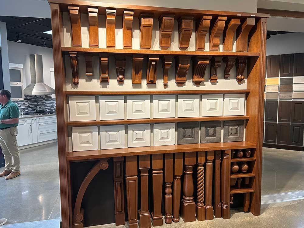 A man in a green shirt stands in front of a display of wooden shelves
