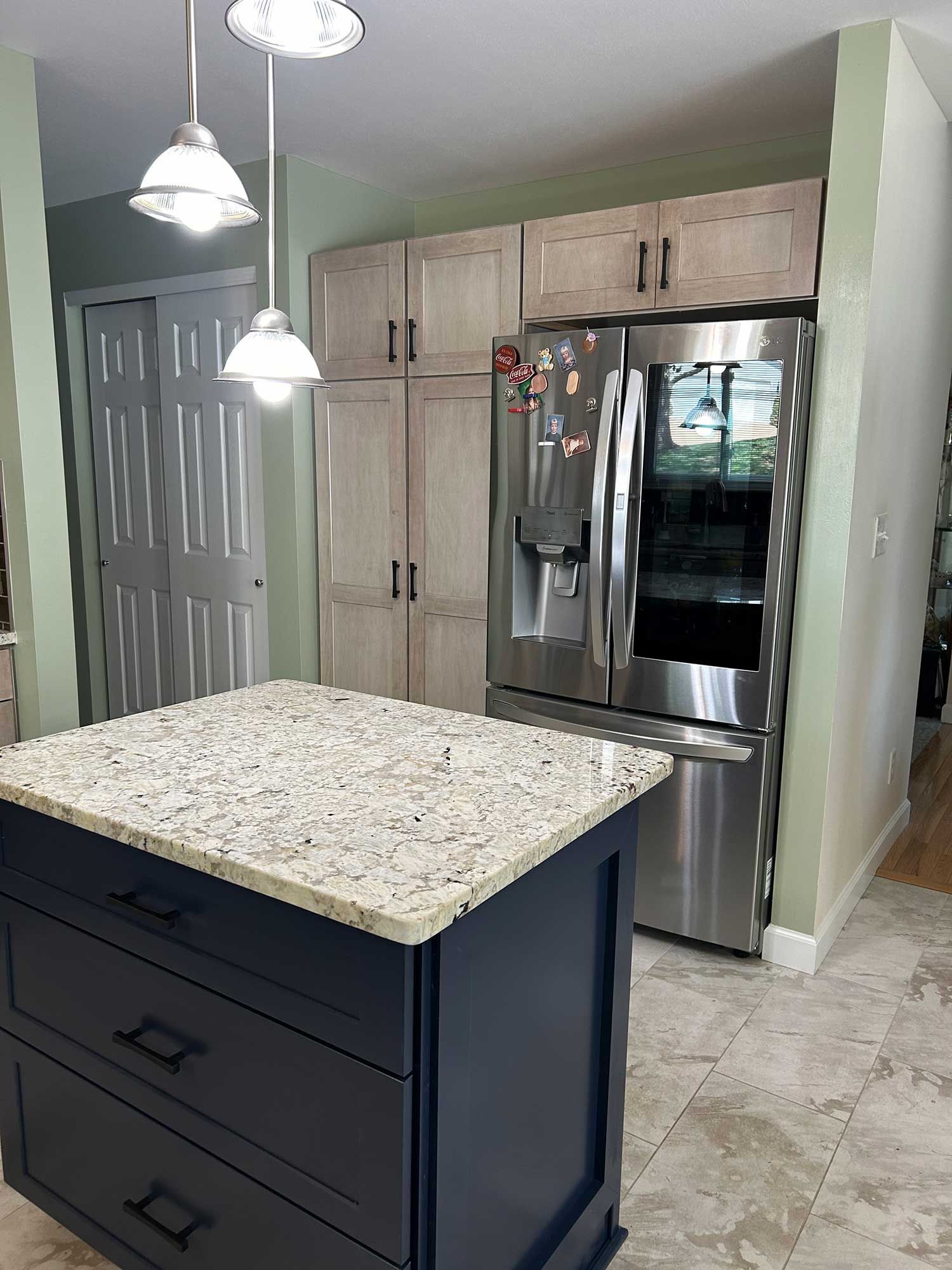 A kitchen with a large island and a stainless steel refrigerator