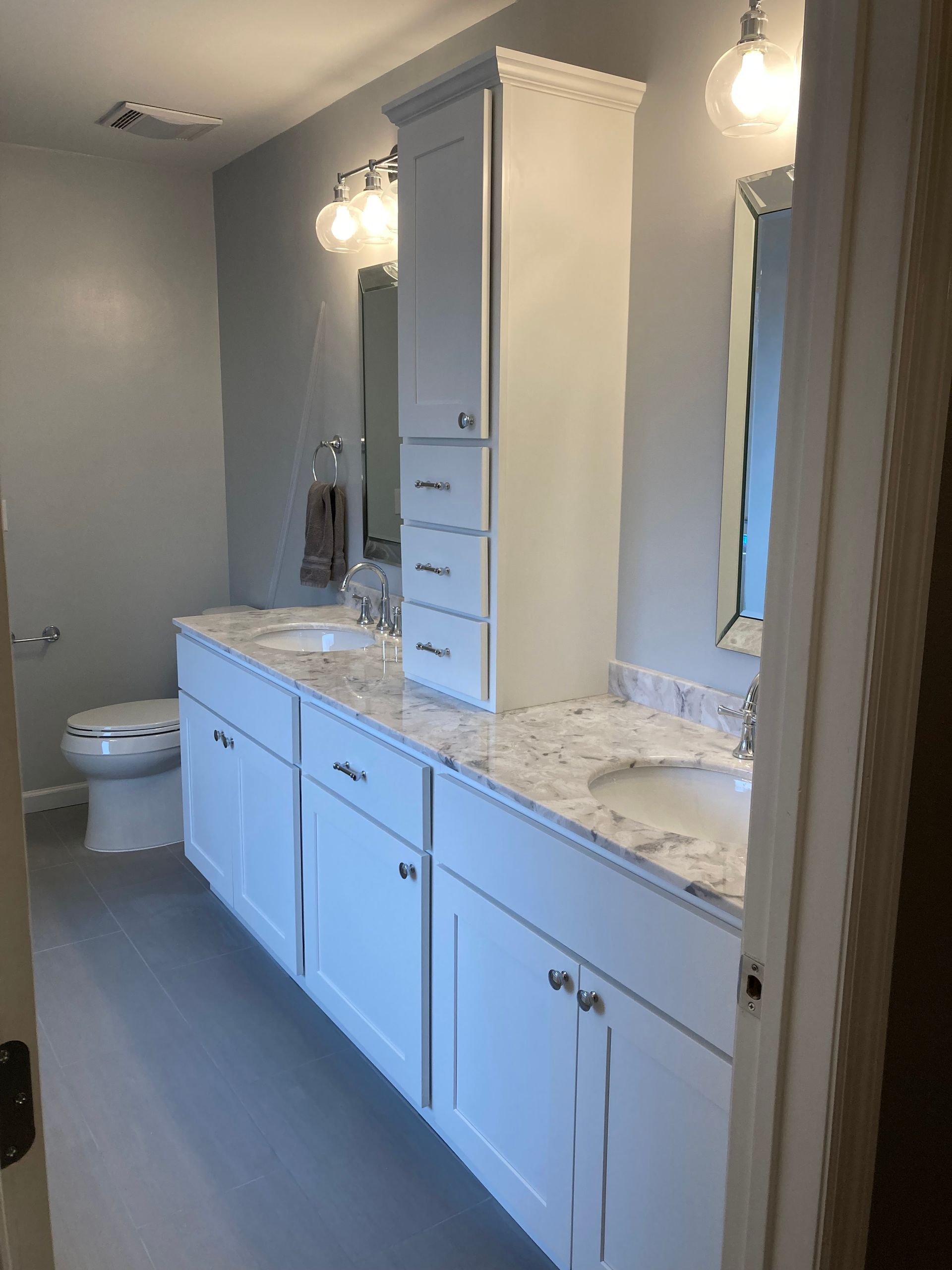 A bathroom with two sinks , a toilet and a mirror.