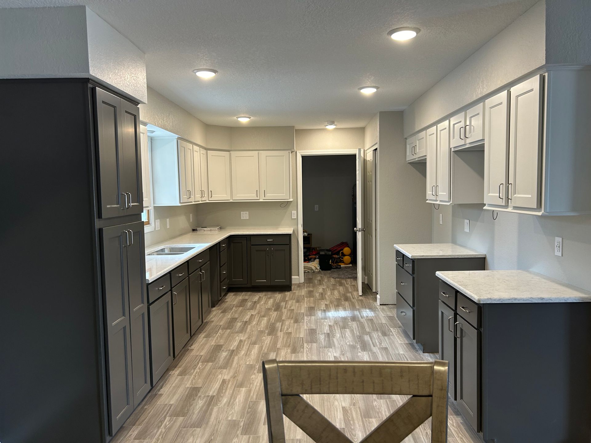 A kitchen with gray cabinets and white counter tops.