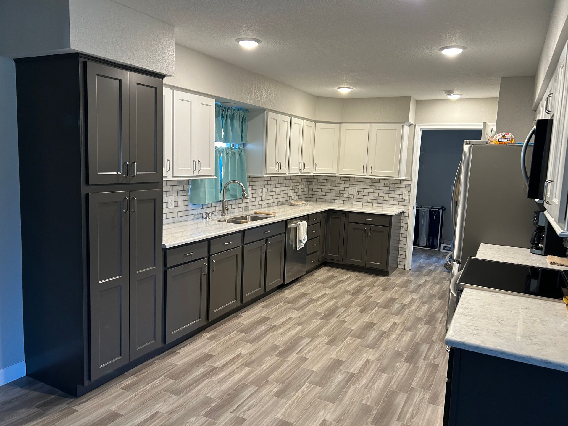 A kitchen with gray cabinets and white counter tops.