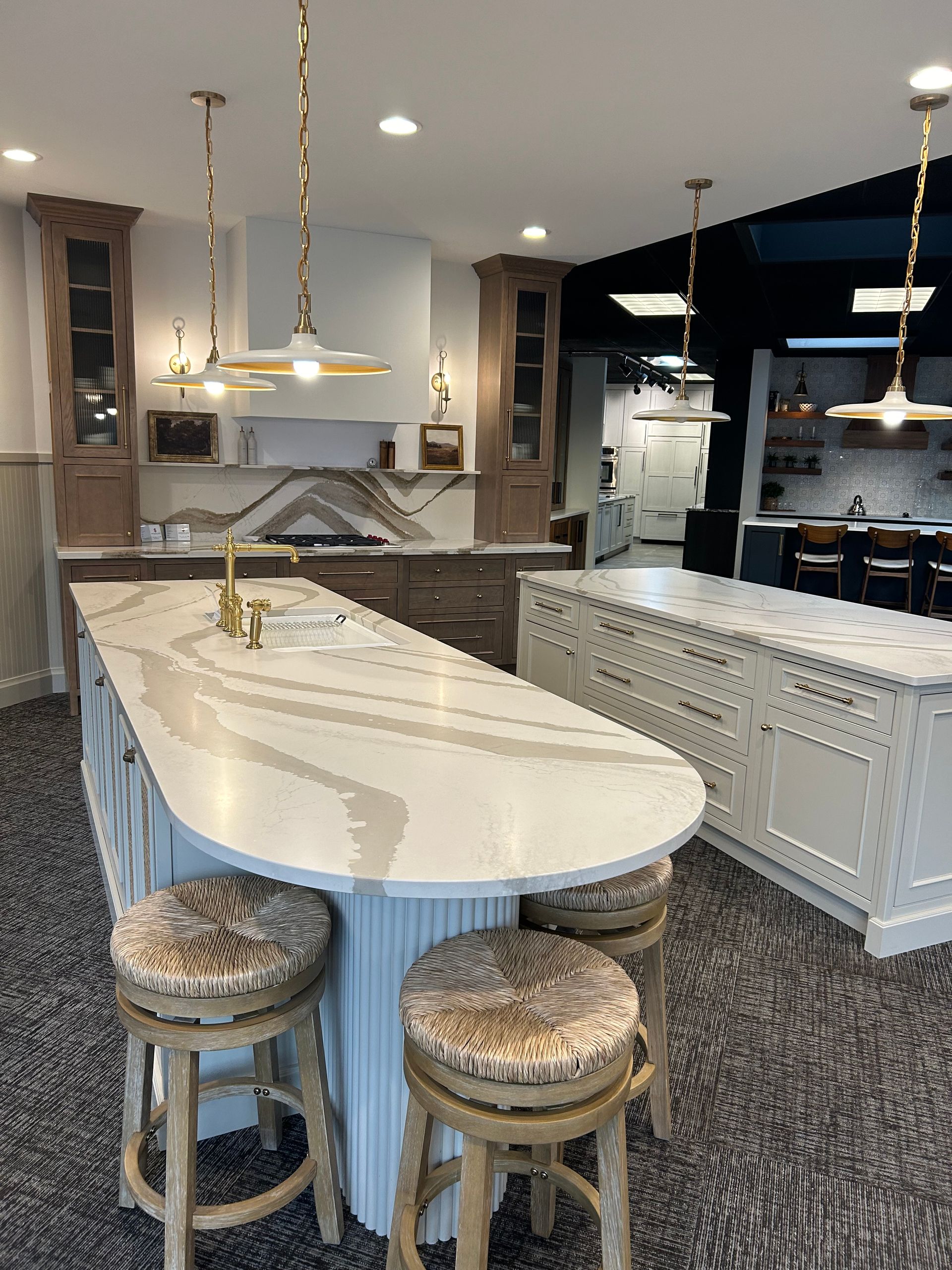 A kitchen with a large island and stools in it.