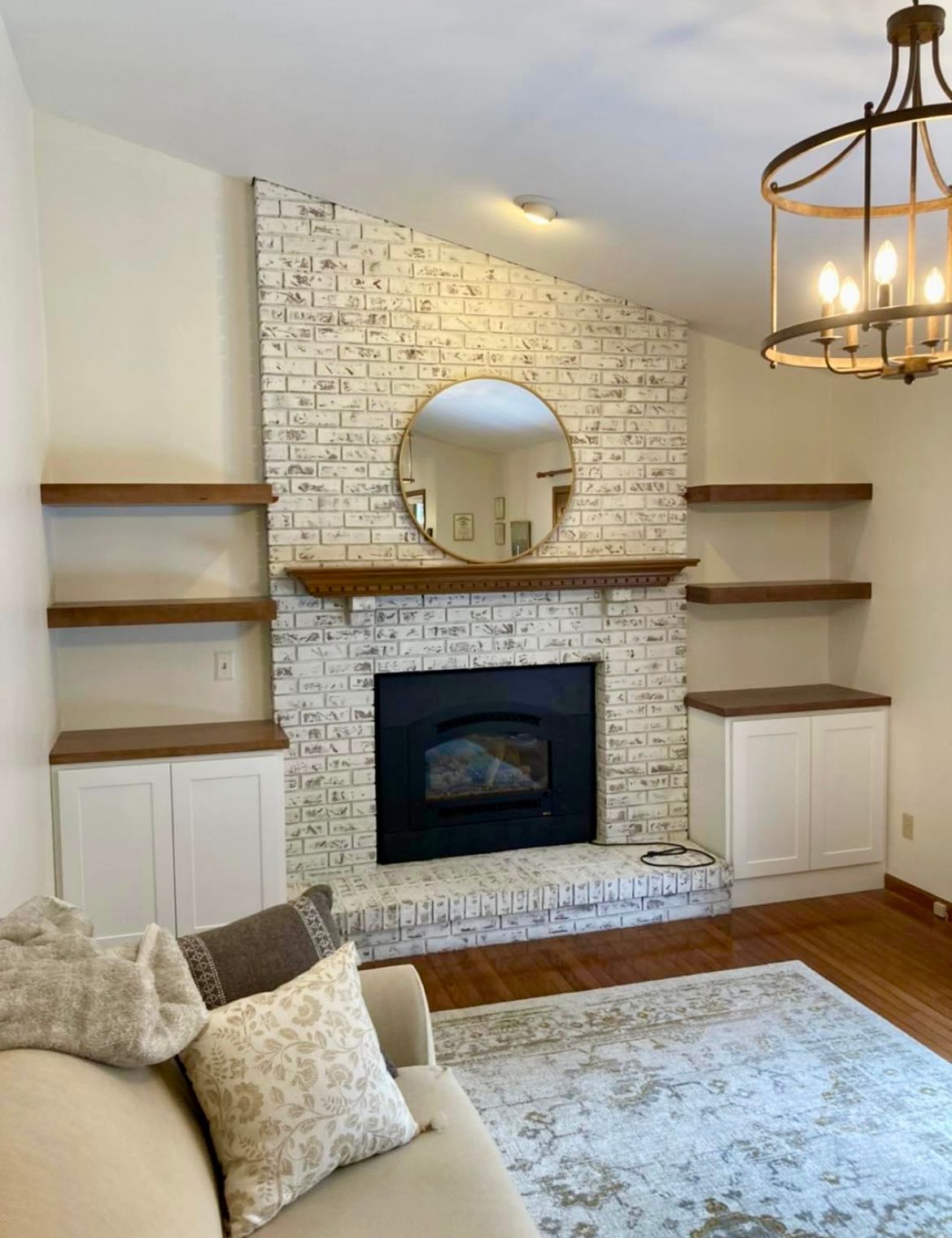 A living room with a fireplace , couch , shelves and a mirror.