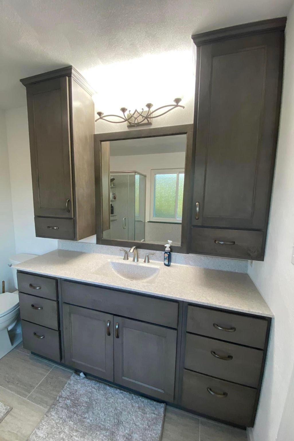 A bathroom with a sink , mirror , cabinets and drawers.