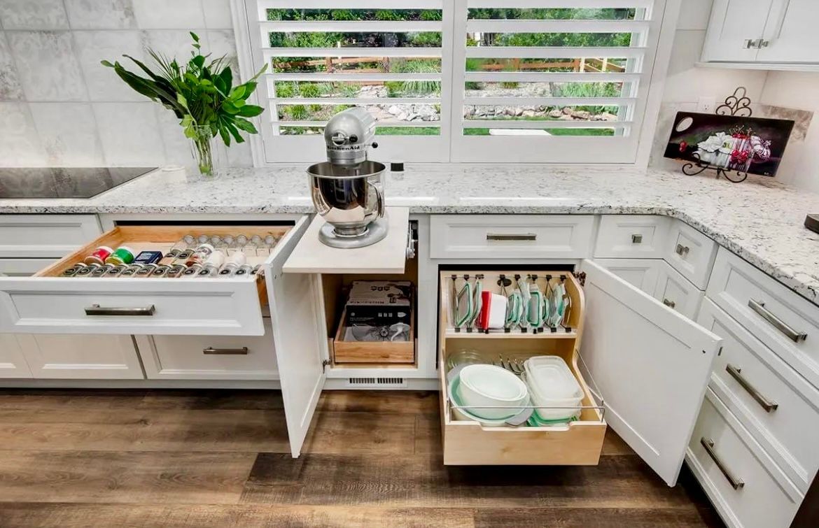 A kitchen with white cabinets and drawers and a mixer in the corner.
