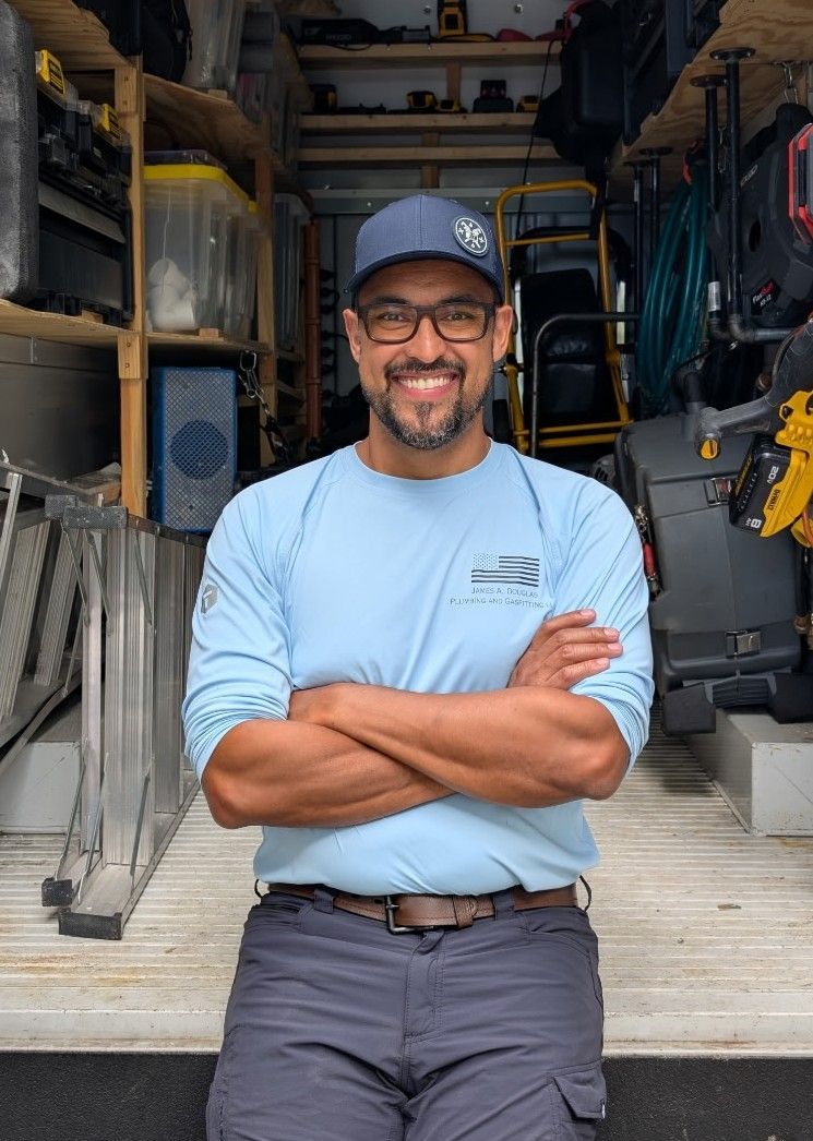 James A Douglas in front of open work truck, arms crossed and smiling warmly