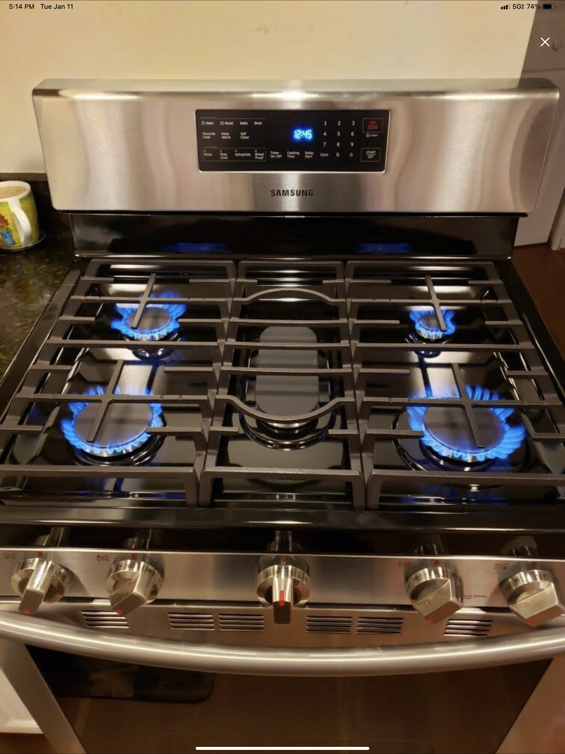 A stainless steel gas stove with four burners and blue flames.