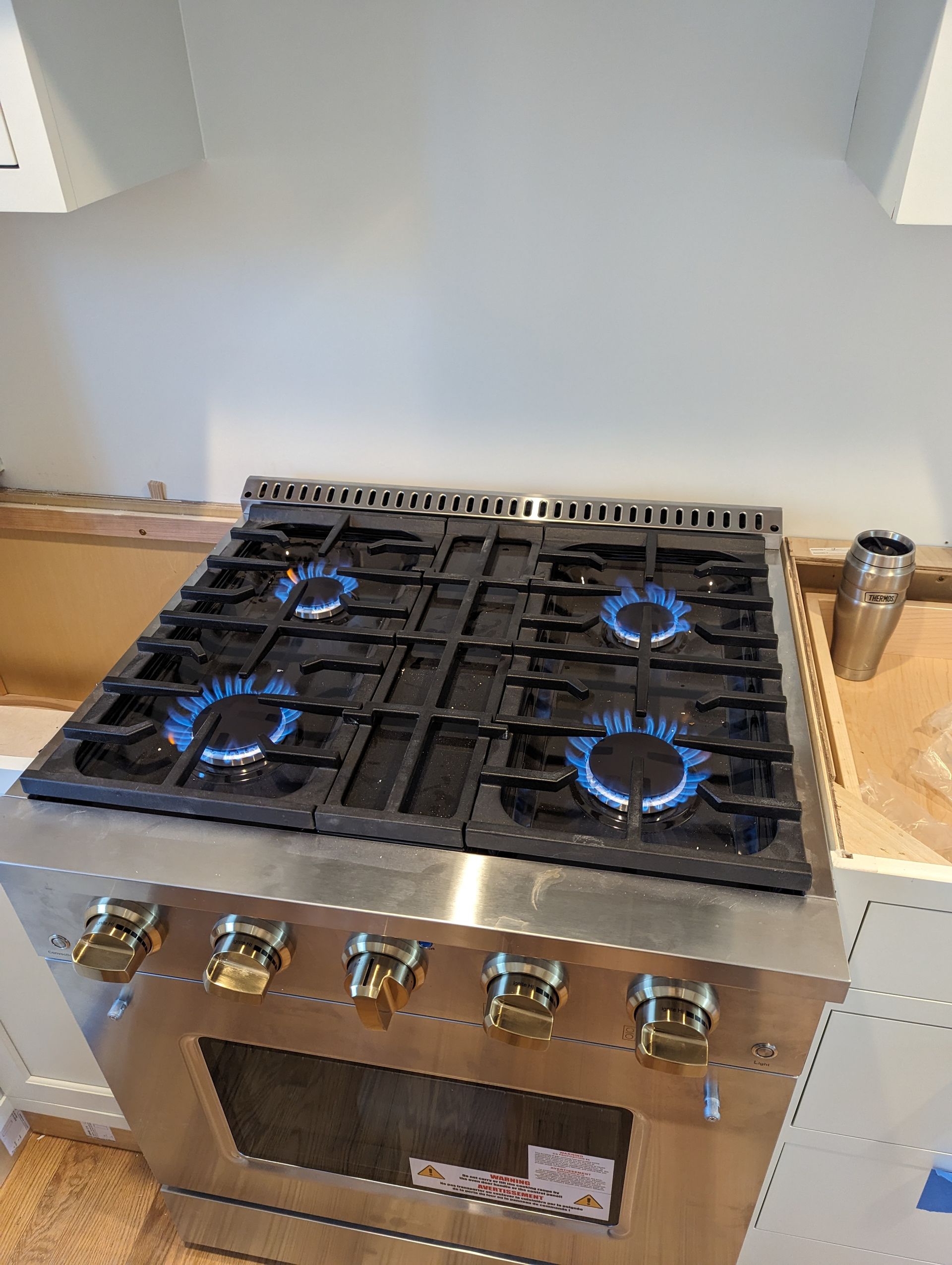 A stainless steel stove with four burners is sitting on top of a kitchen counter.