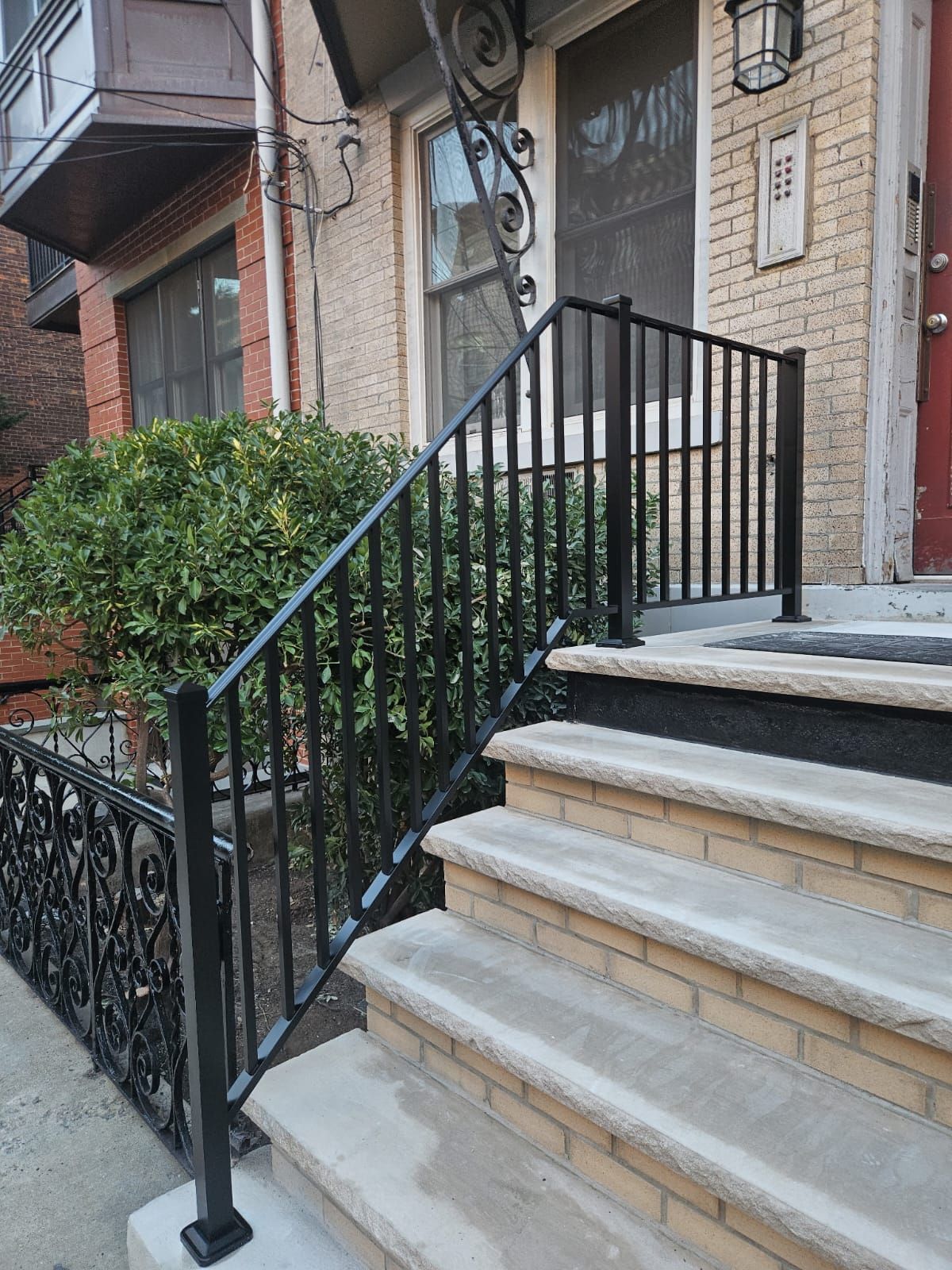 Black metal railing along outdoor concrete steps leading to a building's entrance.