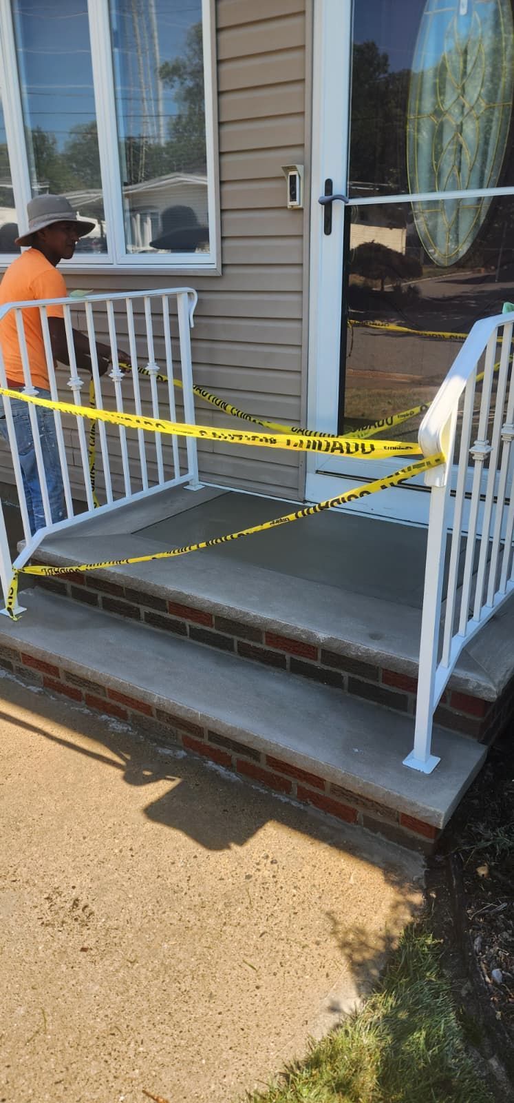 A front porch with yellow caution tape, steps, and a person in an orange shirt.