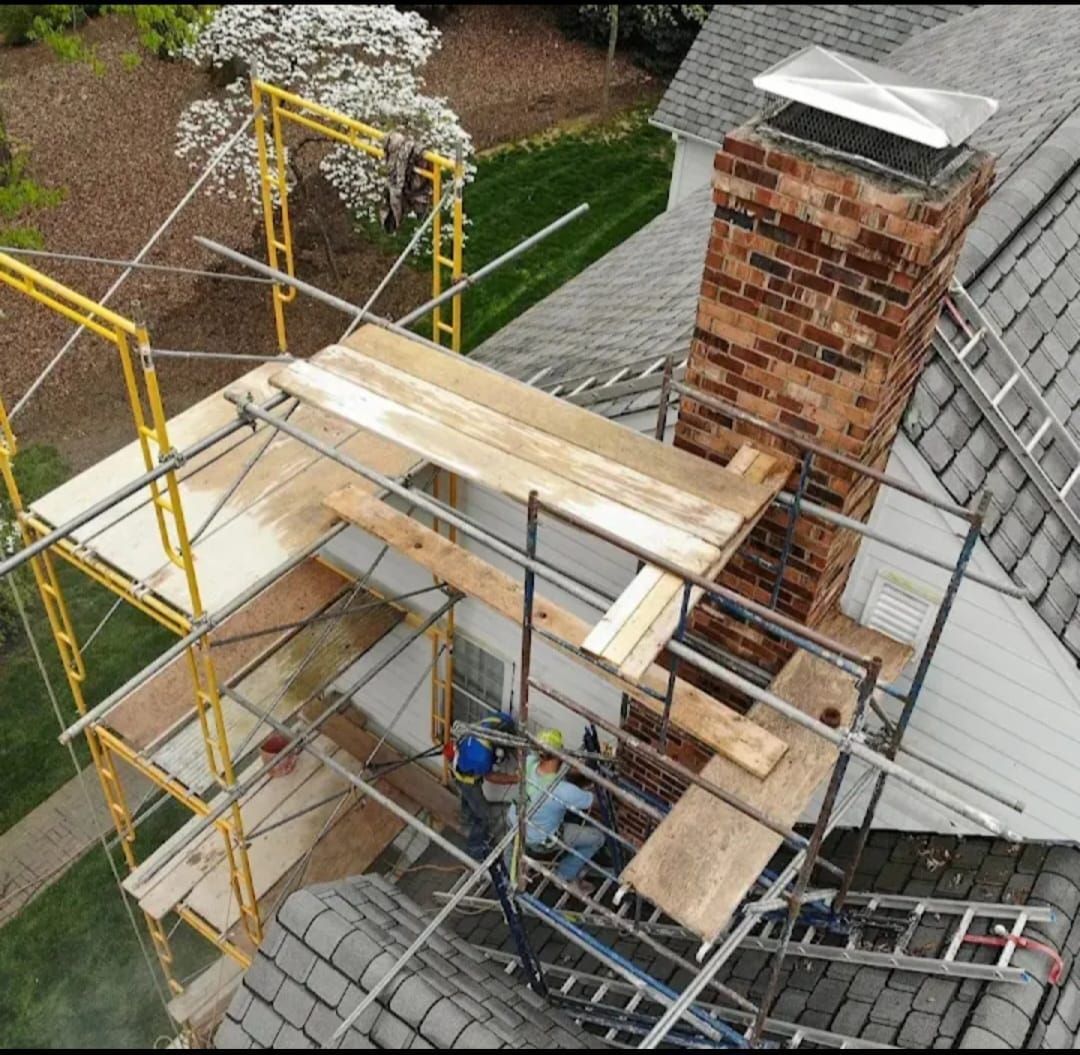 Scaffolding around a chimney on a roof, workers on the platform.