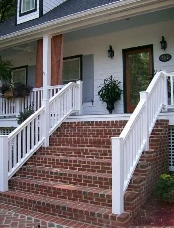 Brick front porch stairs with white railings leading to a house entrance