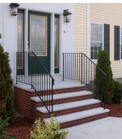 Front steps to a townhouse with brick risers, black railings, and a green front door with sidelights.