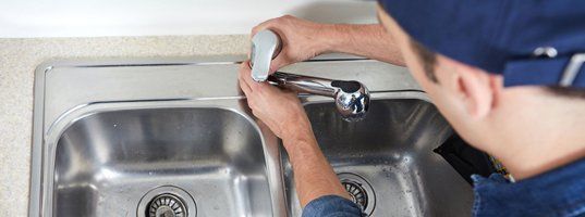 Plumber installing sink in kitchen