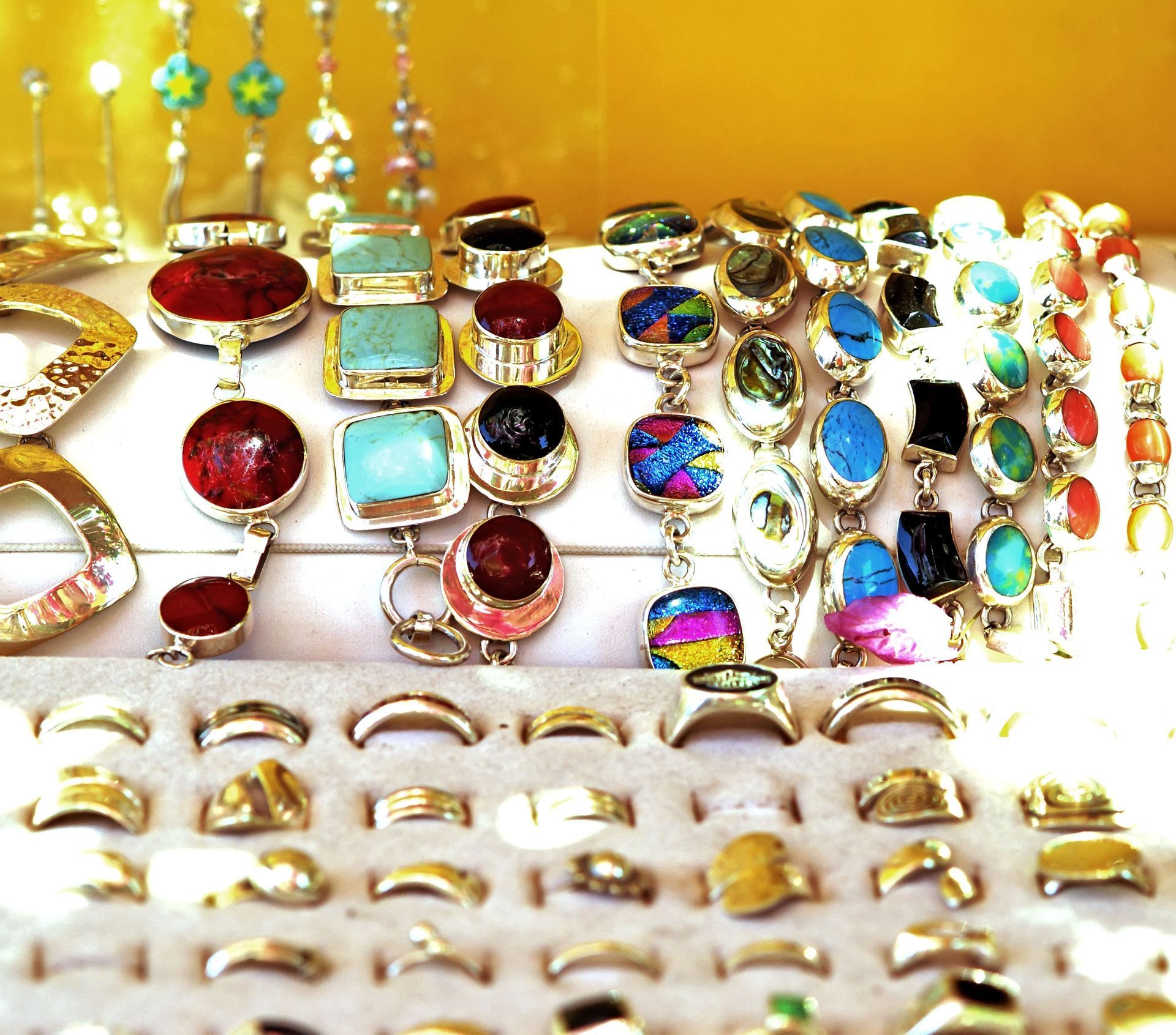 Jewelry display with silver rings and gemstone pendants in various colors.