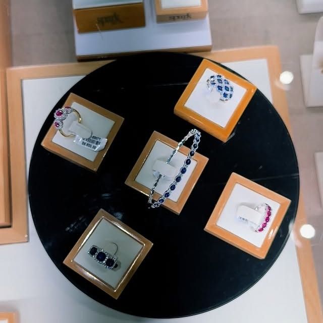 Jewelry display: rings and a bracelet with gemstones on individual display stands.