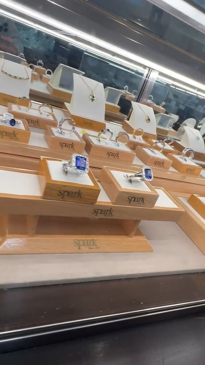 Jewelry display case with necklaces and rings on wooden platforms.