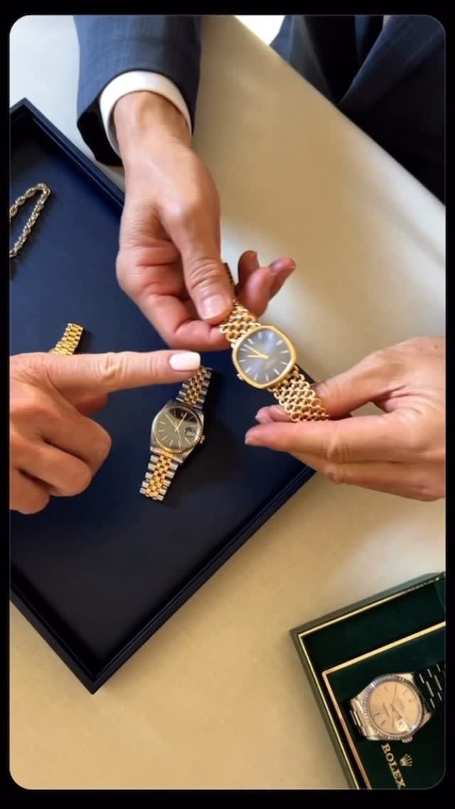 Hands holding gold watches on a blue tray. One person points. Green box with watch in corner.