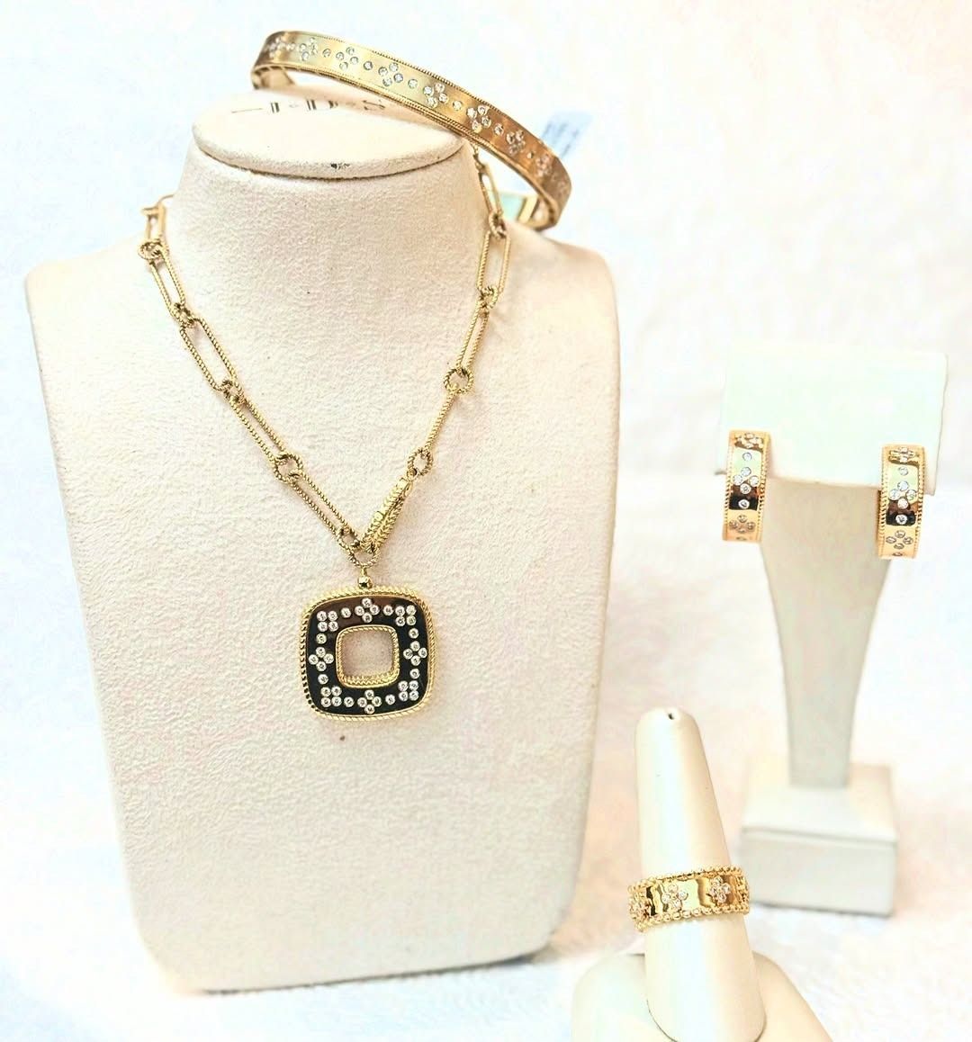 Gold jewelry set: necklace, bracelet, earrings, and ring displayed on white mannequins.