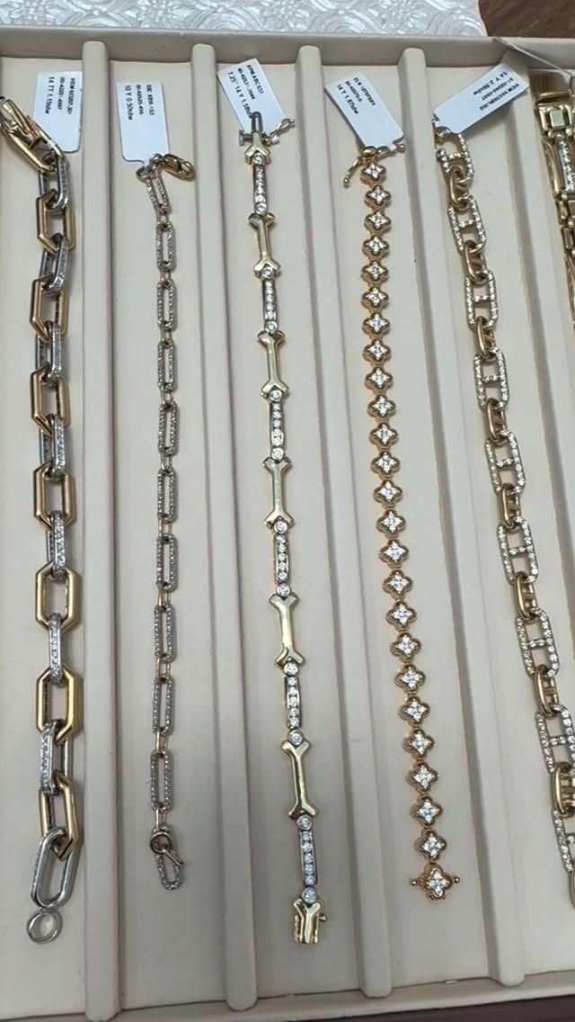 Five gold and diamond bracelets displayed in a jewelry case.