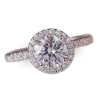 Diamond ring with a round center stone and a halo of smaller diamonds.